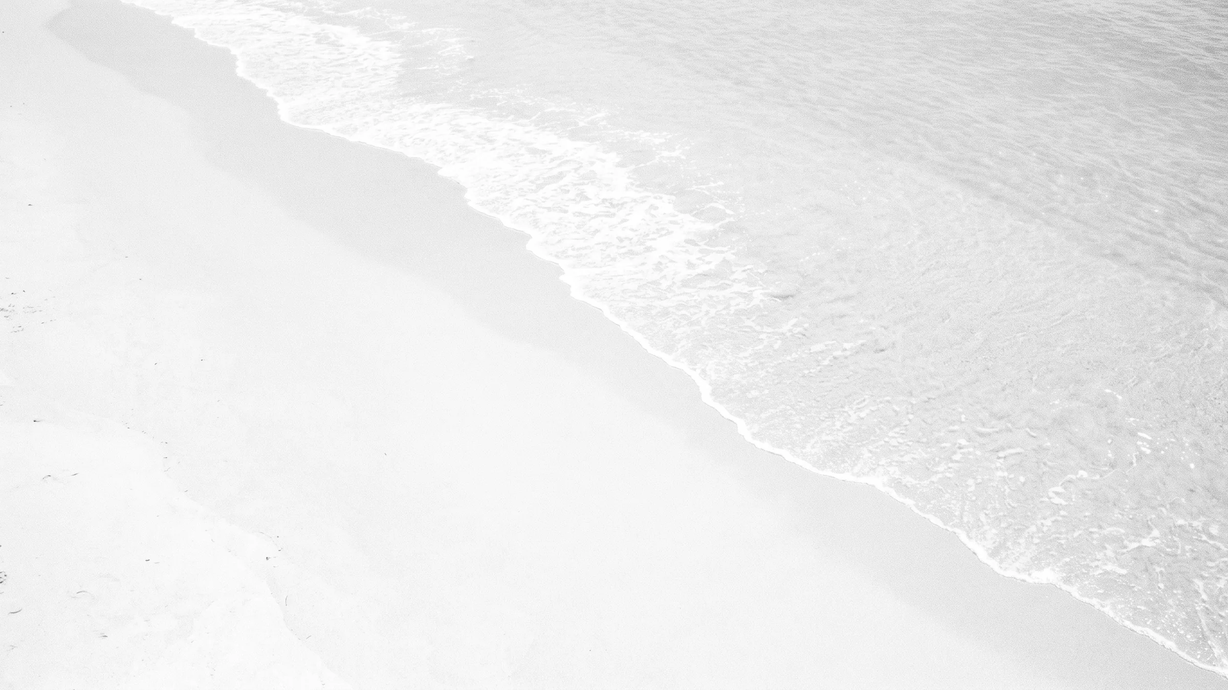 All Luxury Condos: the beach from above, the surf line running diagonally, black and white